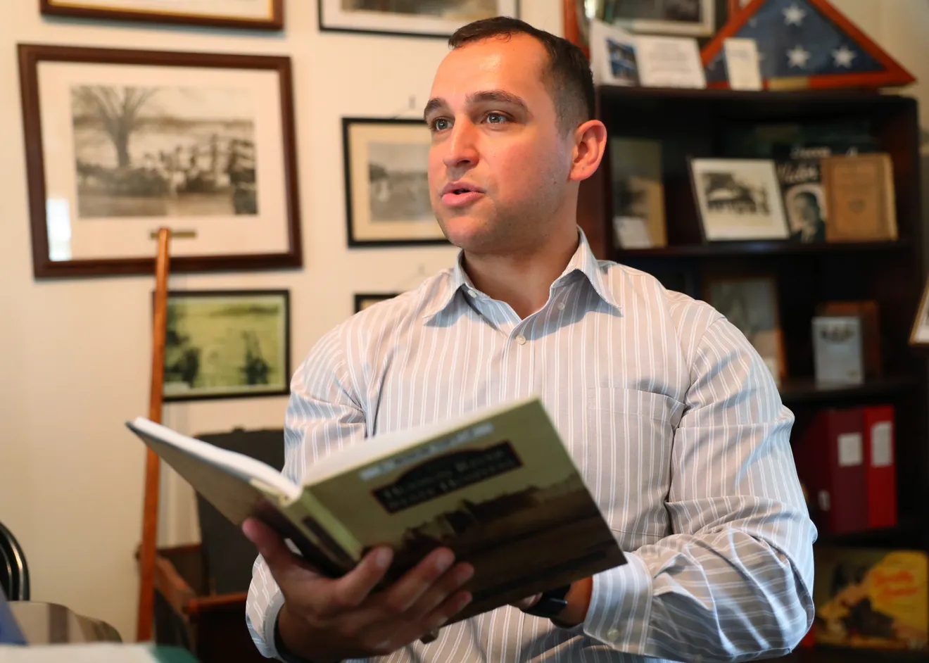 Joseph Galante holding a history book at the Hudson River State Hospital Museum, as photographed for the Poughkeepsie Journal